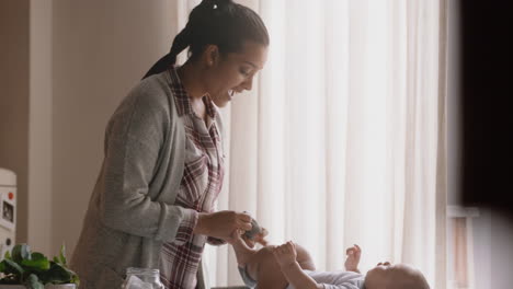 happy mother with baby dressing beautiful toddler caring for infant gentle mom enjoying motherhood nurturing her child at home