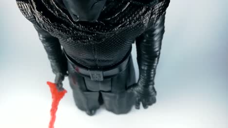 a black plastic action figure of kylo ren holding red lightsaber isolated on a white background, dolly