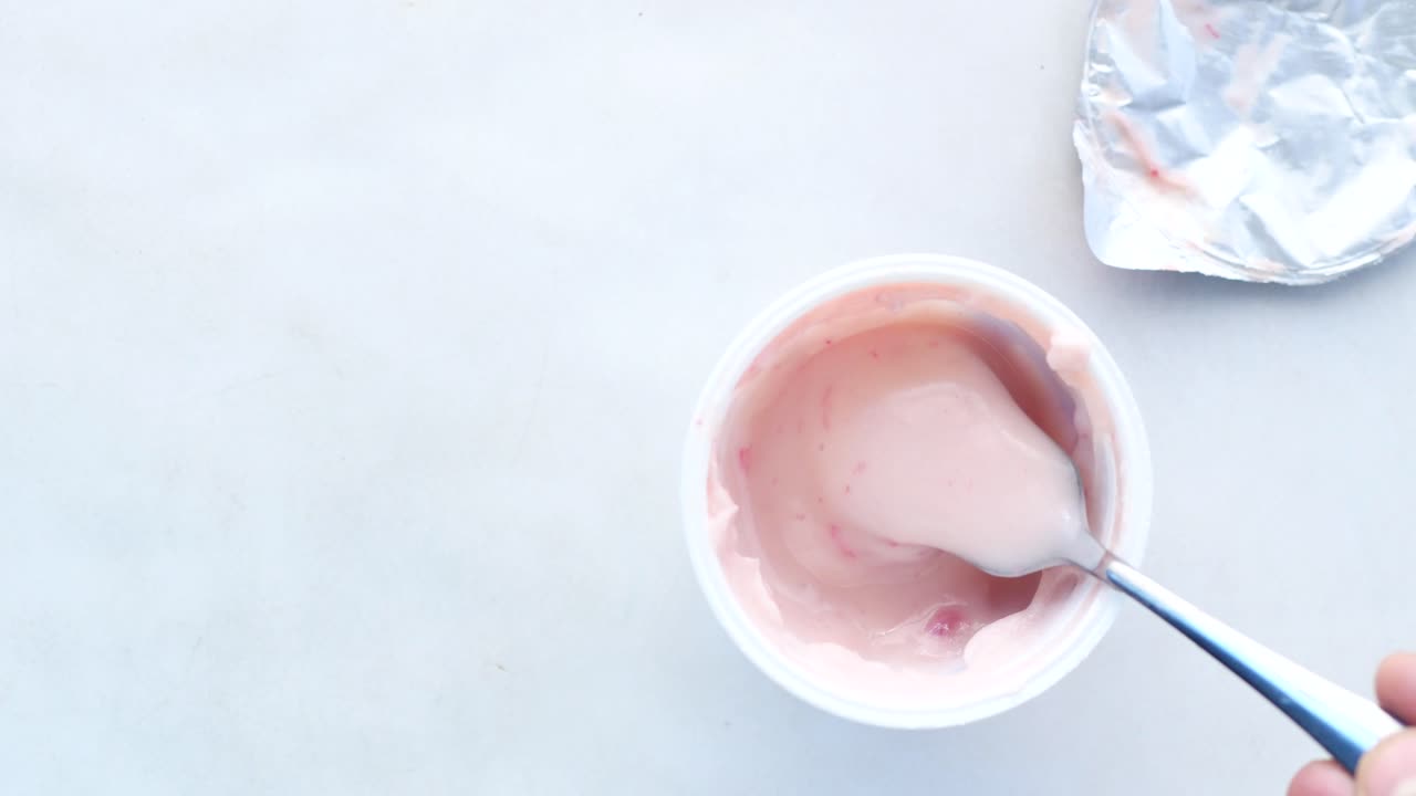yogur rosa en una taza con una cuchara
