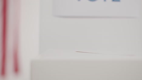 close up of woman casting vote into ballot box in american election