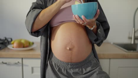 Retrato-De-Una-Mujer-Morena-Embarazada-Comiendo-Ensalada-De-Frutas-En-La-Cocina-En-El-Desayuno-De-La-Mañana.-La-Alimentación-Saludable-Durante-El-Embarazo-Es-La-Clave-Para-Un-Bebé-Sano.