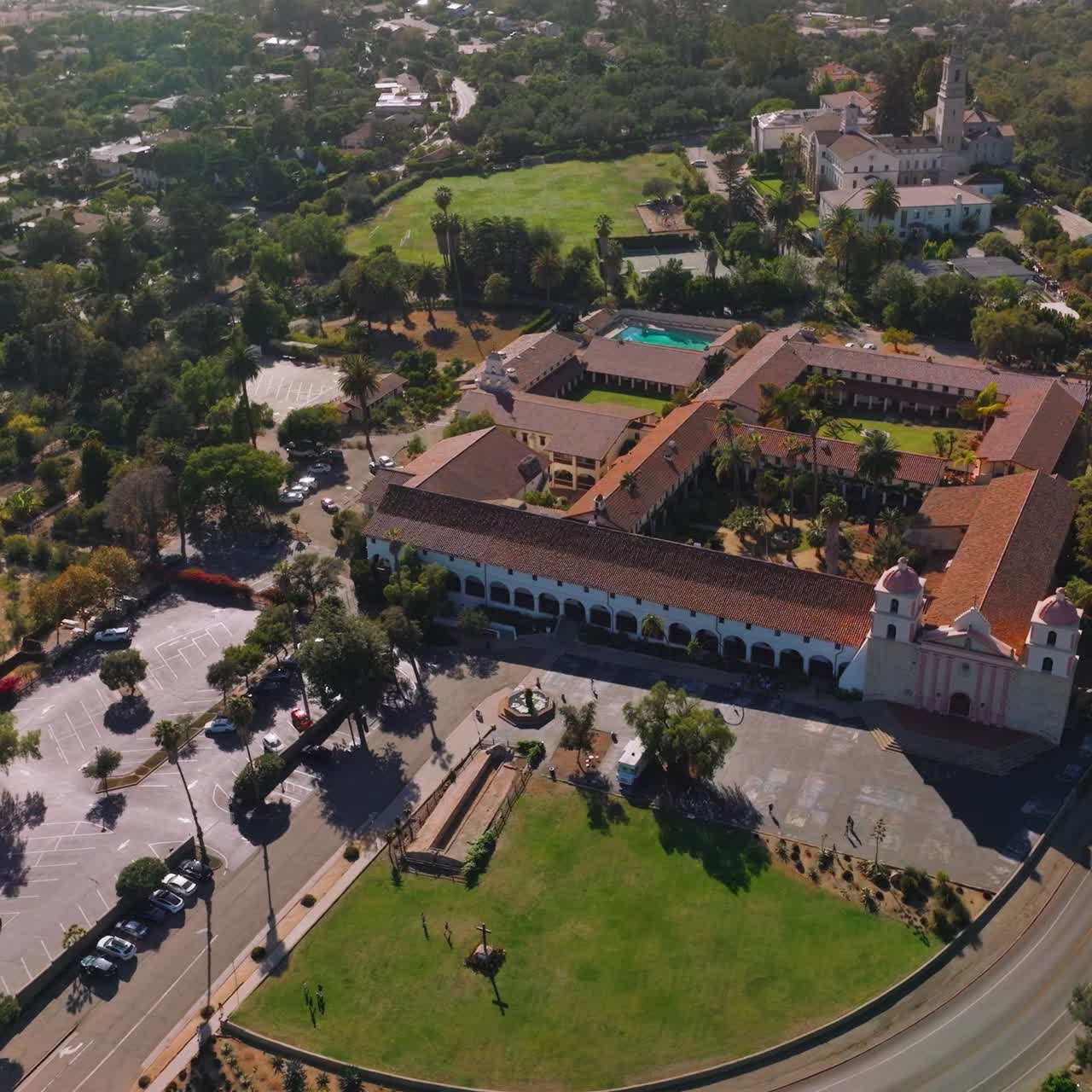 Green city scenery on summer day. Approaching beautiful Old Mission Santa Barbara with a lively traffic road. Top view