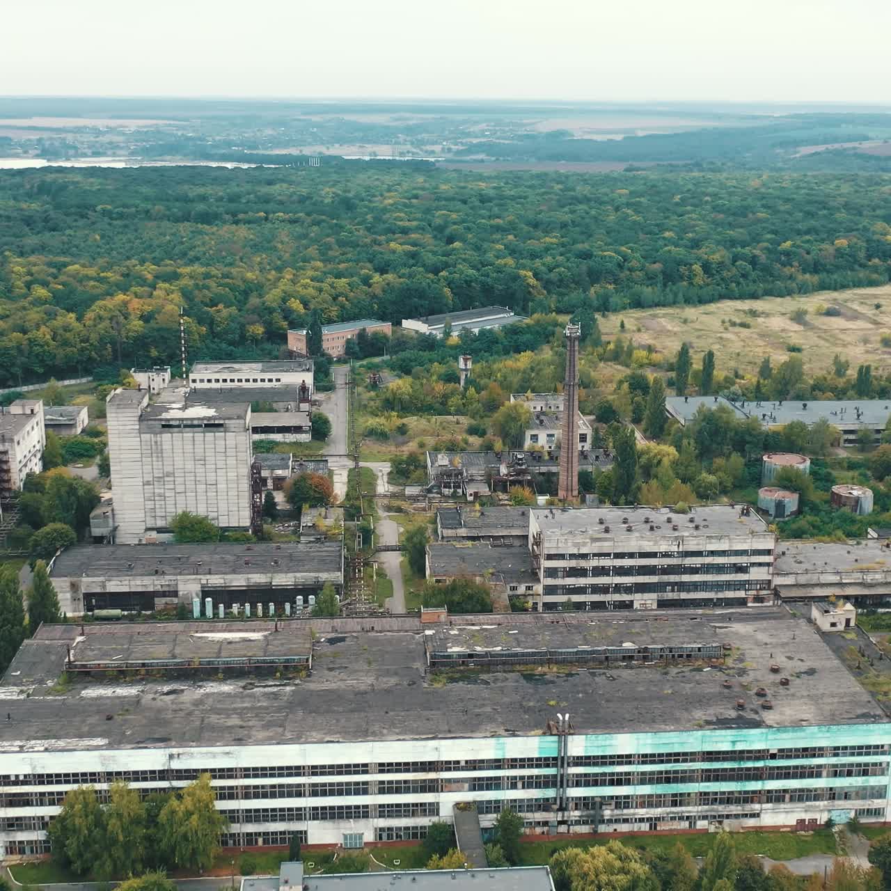 Large industrial territory on nature background. Many buildings of abandoned factory in the countryside. View from above