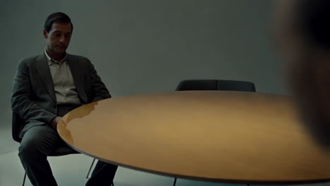 a man in a suit sits at a round table