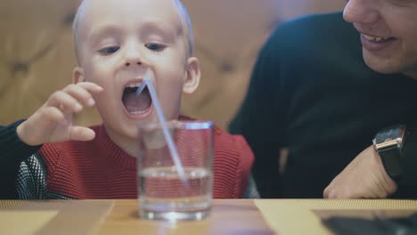 un niño tremendo hace burbujas soplando en un vaso de agua