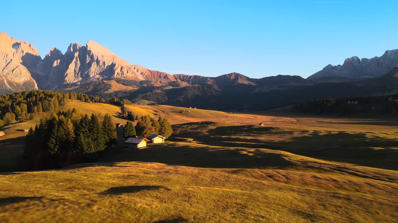 Mountains, forest and grass fields with wooden cabins filmed at Alpe di Siusi inEuropean Alps, Italian Dolomites filmed in vibrant colors at sunset