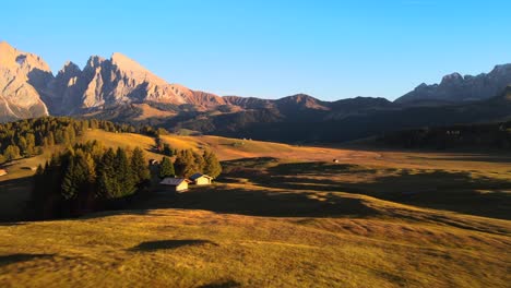 Mountains,-forest-and-grass-fields-with-wooden-cabins-filmed-at-Alpe-di-Siusi-inEuropean-Alps,-Italian-Dolomites-filmed-in-vibrant-colors-at-sunset