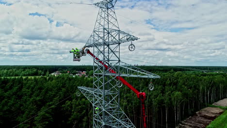 Aerial-view-of-engineers-on-a-crane,-repairing-power-lines-on-a-electric-pylon