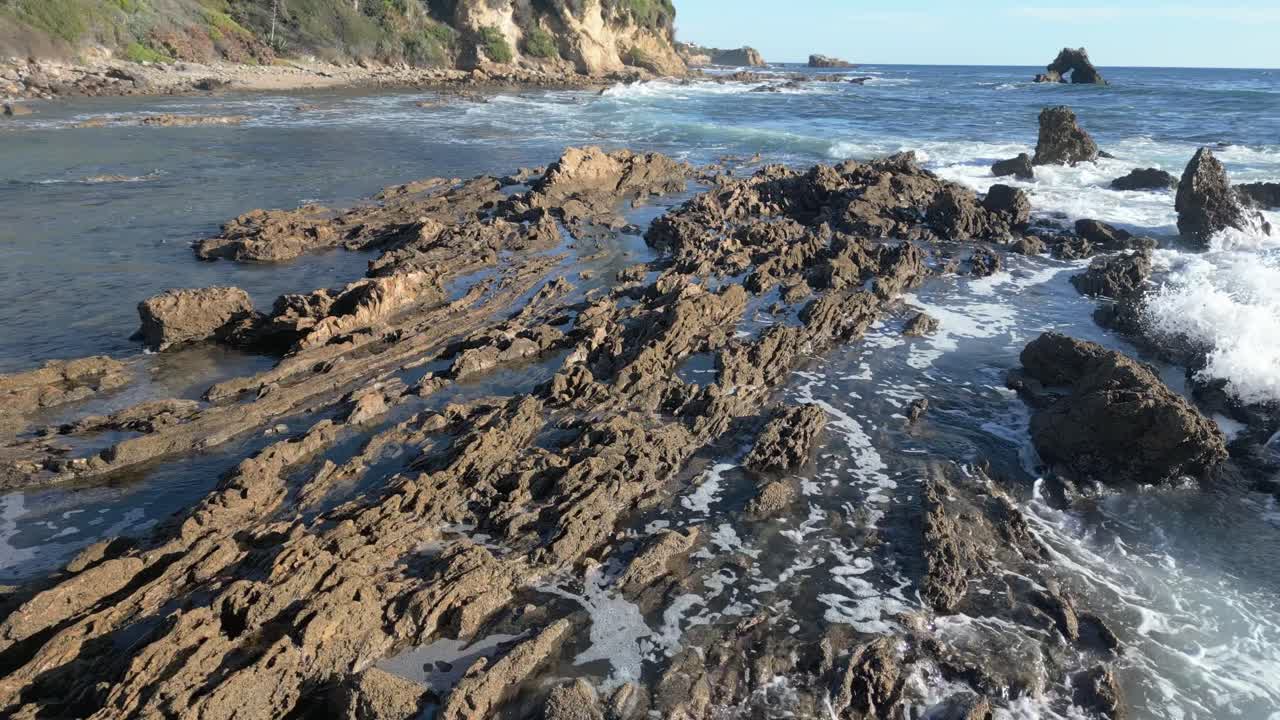 Calm 4K drone shot flying over rocks along Laguna Beach shoreline. Slow motion capable, ideal for ocean, nature, travel, or cinematic projects