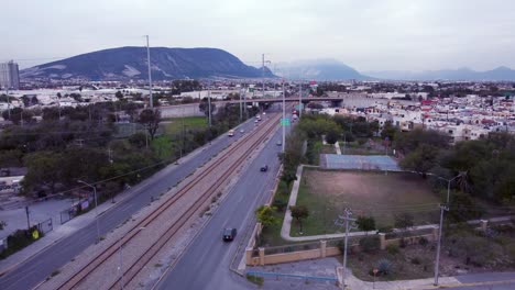 Aerial-shot-of-train-tracks-in-San-Nicolas-de-los-Garza,-crane-up,-cloudy-day