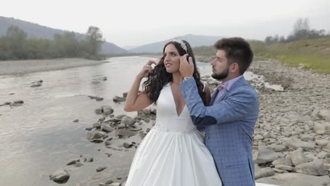 pareja de bodas de pie cerca del río de la montaña. novio y novia enamorados