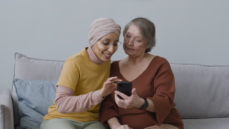 Arabic-Woman-Teaching-An-Elderly-Woman-To-Use-A-Smartphone