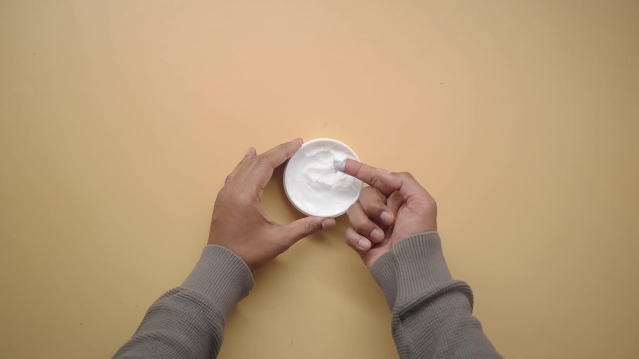 Vista dall'alto di una mano che immerge un dito in una crema bianca