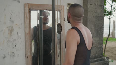 man checking appearance in a mirror at the beach