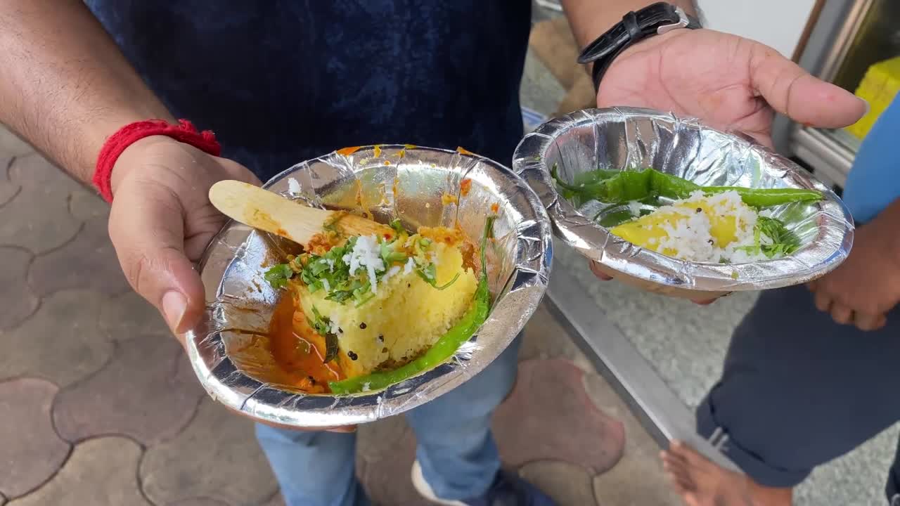 primer plano de un hombre sosteniendo dhokla y gatta un plato típico de gujarat