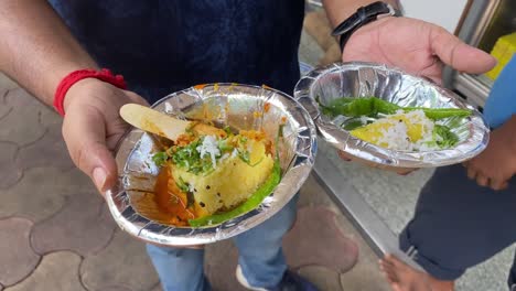 close up shot of a man holding dhokla and gatta a typical gujarat dish