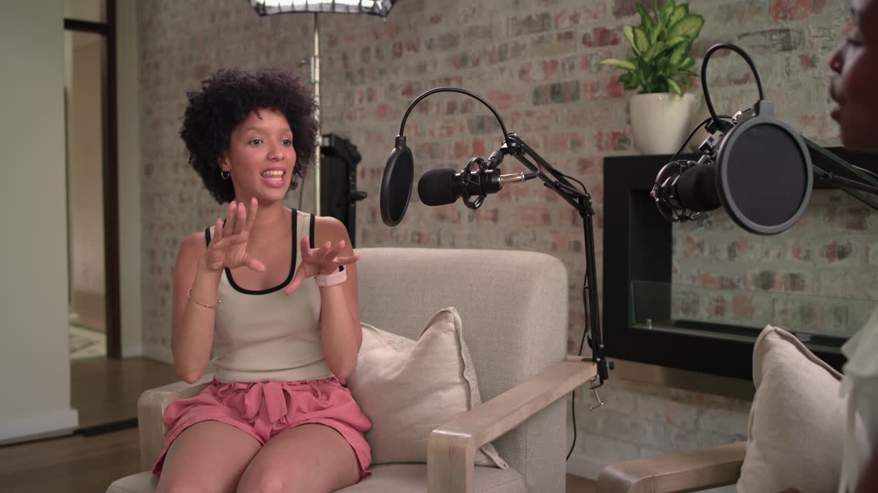 African American female host and guest, host asking via tablet, guest speaking into mic gesturing