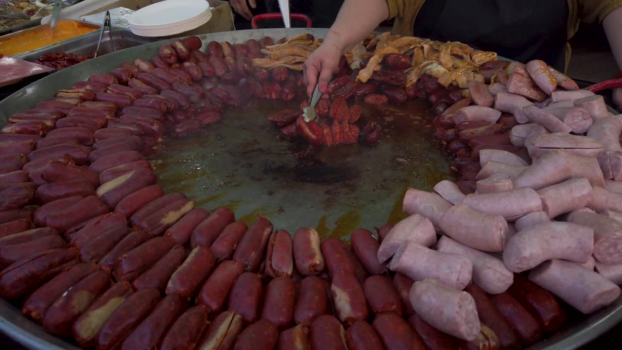 Donna che sistema salsicce di chorizo tagliate su un'enorme padella, primo piano, rallentato