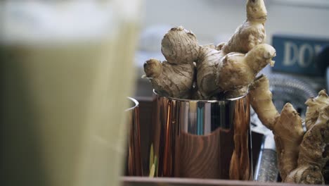 Nice-shot-of-ginger-being-blended-with-a-cluster-of-fresh-ginger-inside-of-a-copper-colored-cup