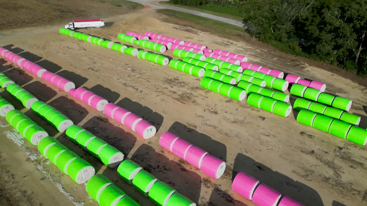Hasat lojistik operasyonları sırasında Amerika Birleşik Devletleri, Alabama, Henry County, Headland yakınlarındaki tarım arazisinde sarılı pamuk balyası sıralarına yaklaşan pamuk modül taşıyıcı kamyonunun hava görüntüsü