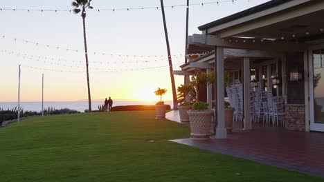 A-couple-watching-the-sunset,-over-the-ocean,-in-their-back-yard-at-golden-hour