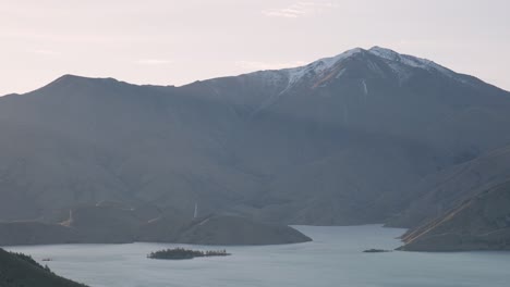 Golden-sunrays-shining-through-gaps-in-rugged-mountain-range-at-Lake-Benmore