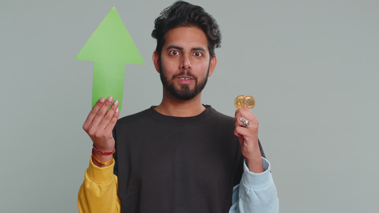 Indian man winner holding arrow sign pointing up showing golden bitcoins cryptocurrency mining btc