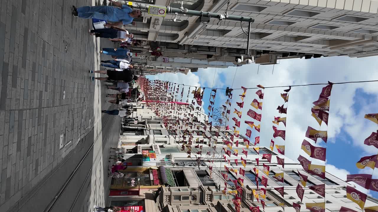 Strada vivace della città decorata con bandiere rosse e gialle e persone che camminano