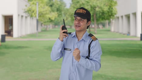 happy indian security guard giving instructions on walkie talkie