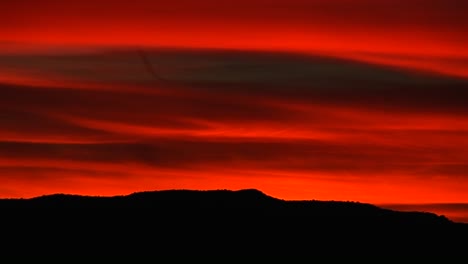 un cielo rojo brillante brilla sobre una montaña rodante