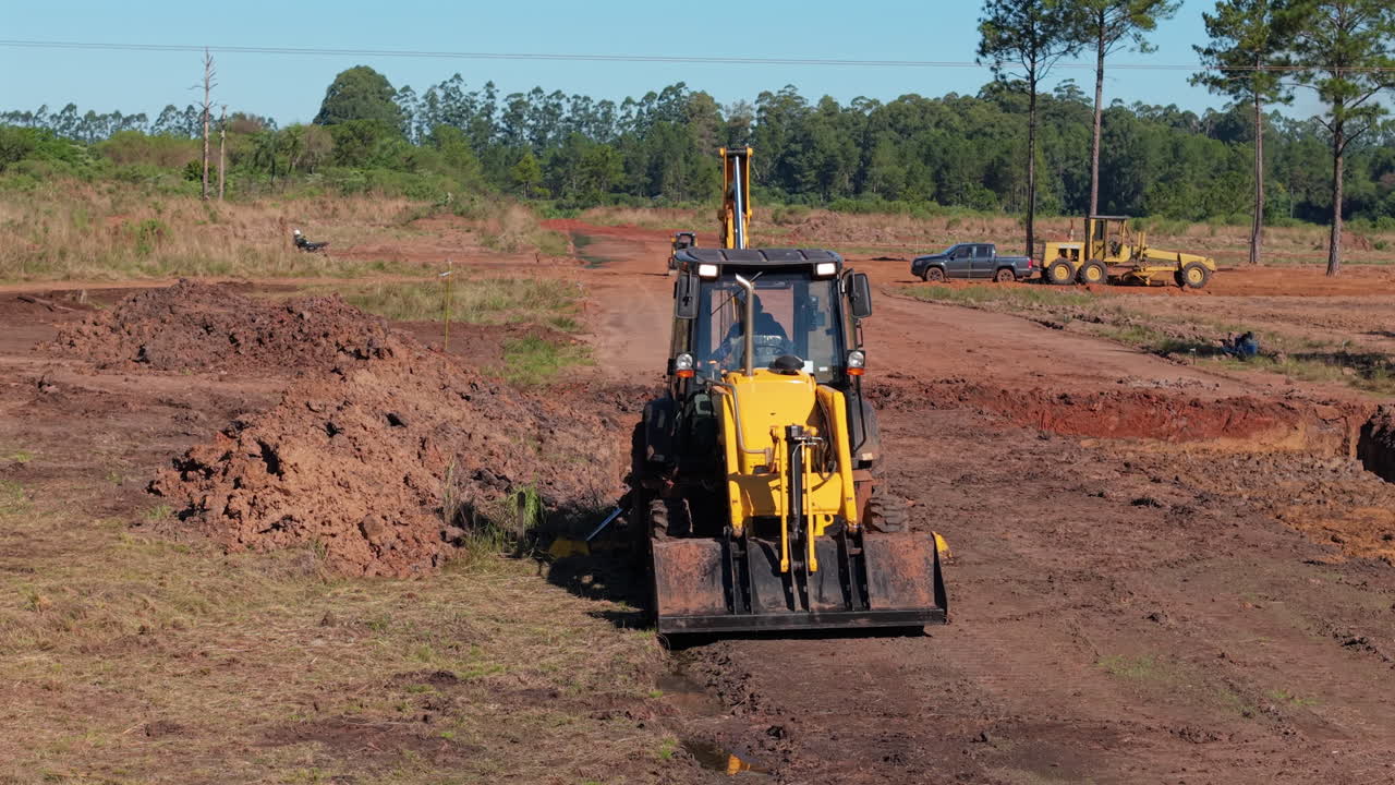 Front view of yellow bulldozer at construction site on red earth terrain while working on it.
