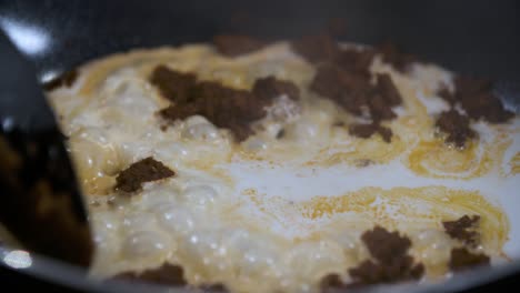 saltee la pasta de curry panaeng con leche de coco fresca en una sartén negra antiadherente