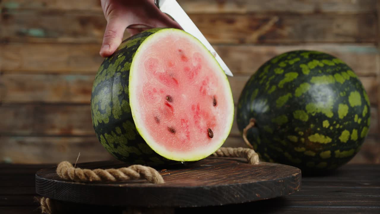 칼로 수박을 나무 트레이에 잘라낸 남자 손.