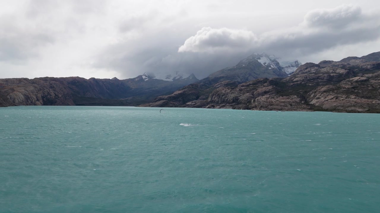 Lago Argentino, Parco Nazionale Los Glaciares, Santa Cruz, Argentina, con acque glaciali turchesi, creste andine di granito, campi di neve e nuvole temporalesche lungo il fronte montuoso patagonico, statico.