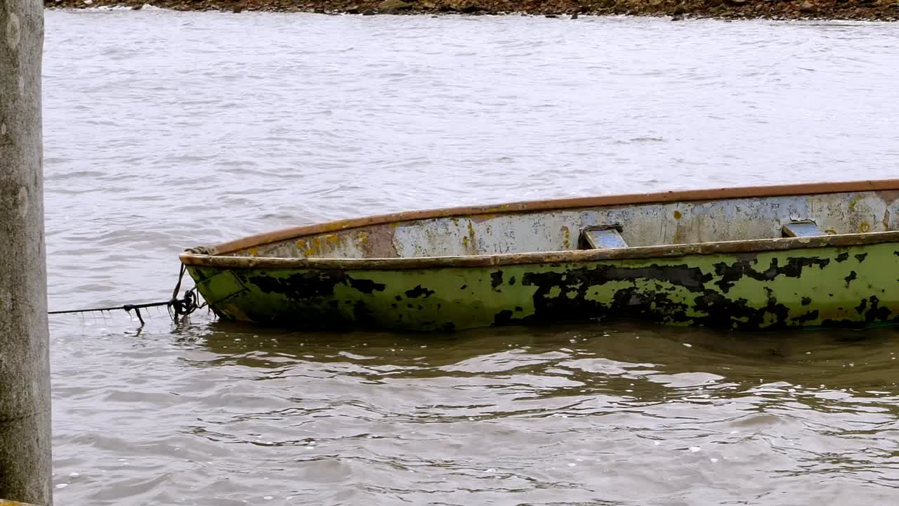 el barco desgastado se desvía en el puerto y es movido por las olas.