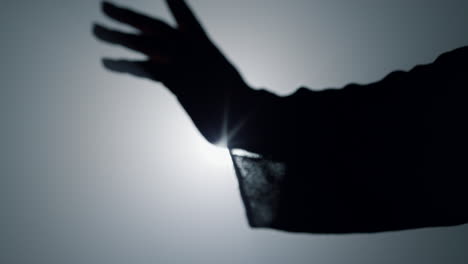 silueta de la mano de la mujer en el fondo de los reflectores. niña moviendo el brazo y los dedos.