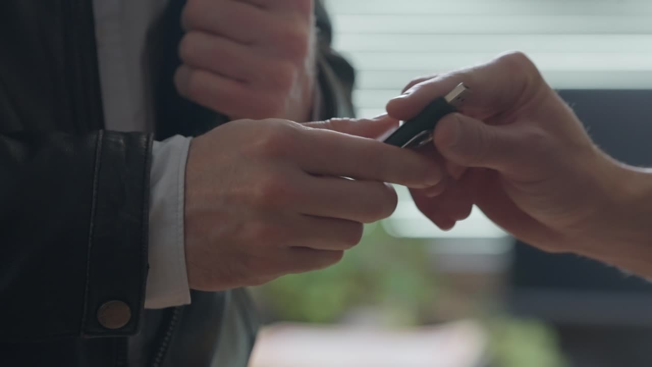 Hand discreetly pulling a USB stick from a jacket pocket and handing it to another person. Data transfer, hacking, confidential exchanges. cybersecurity, corporate leaks, intelligence operations.