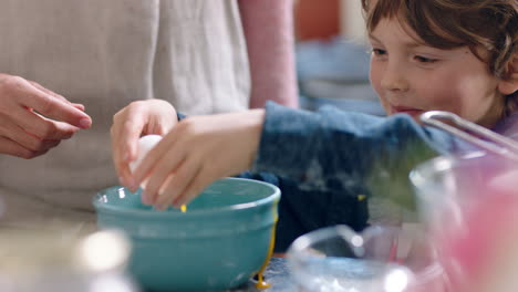 niño lindo ayudando a la madre a hornear en la cocina mezclando ingredientes rompiendo huevos en el cuenco preparando la receta en casa con la madre