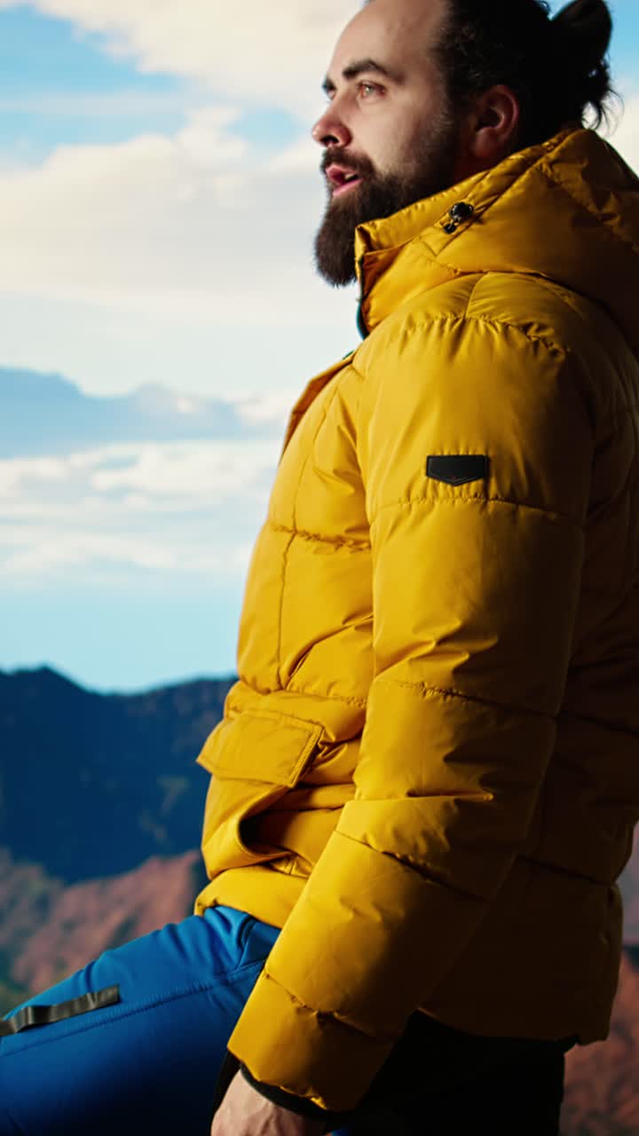 Man in Yellow Jacket Puts on Hood While Admiring Mountain View