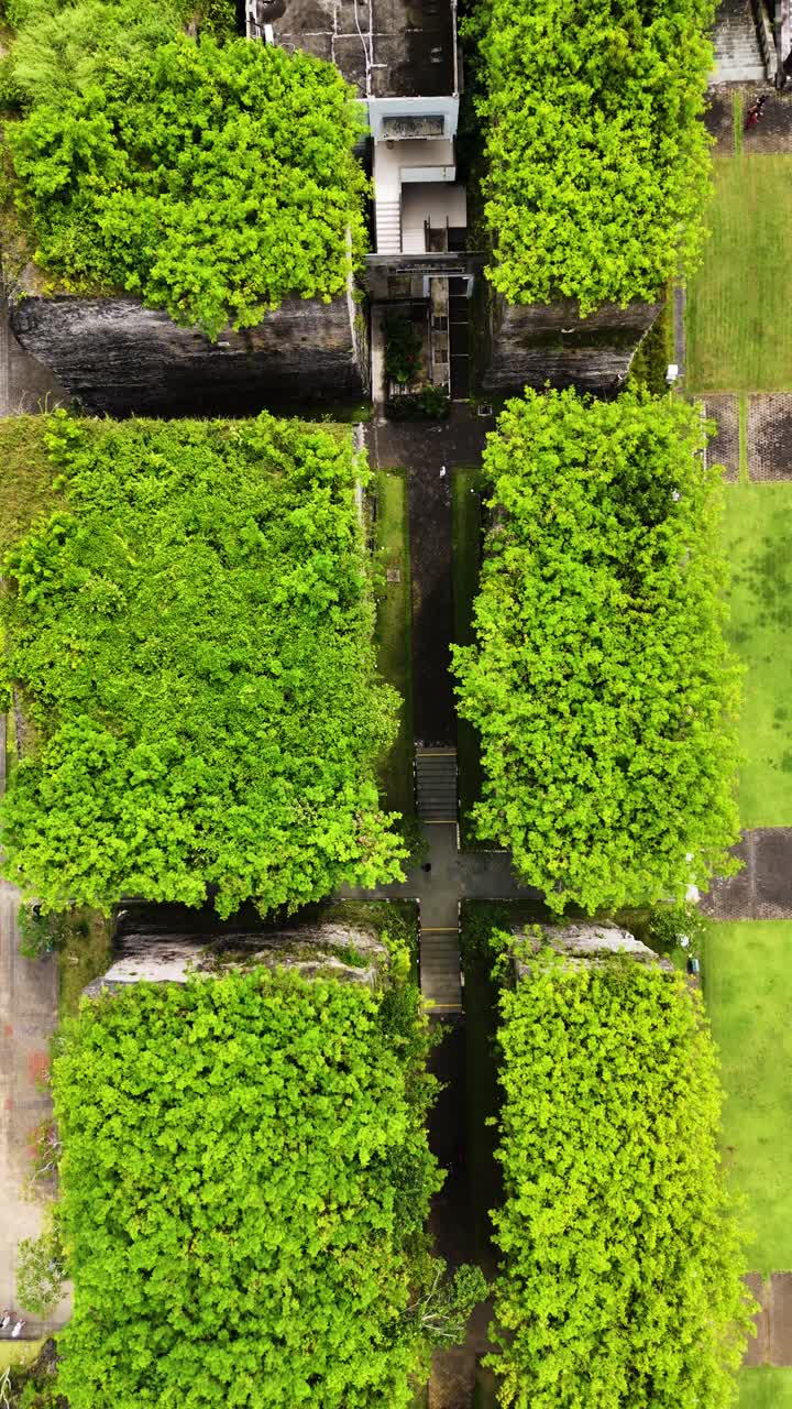 Green park with tall stone block in Garuda Wisnu Kencana park, aerial top down vertical view