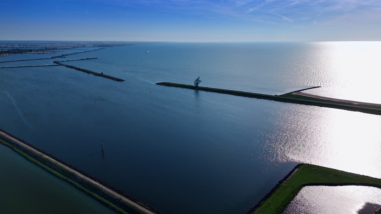 Sun reflects on the surface of the vast waterscape. Dams on the Markermeer Lake in Lelystad, Netherlands. Aerial view.