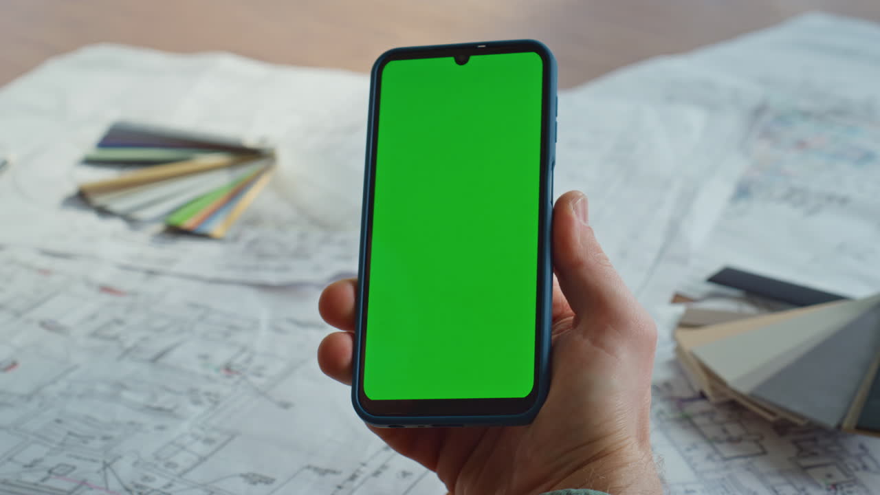 Manager hand holding green screen smartphone in architectural agency closeup
