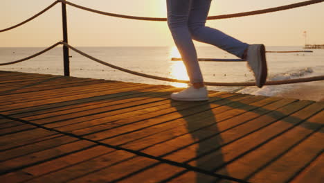 Morning-Jog-On-The-Pier-When-The-Sun-Rises-Over-The-Sea-In-The-Frame-Only-The-Legs-Are-Visible-Stead