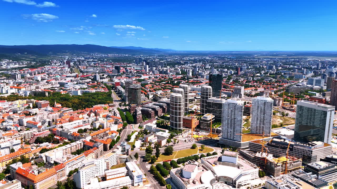 Bratislava skyline view during sunny day. Vibrant cityscape of Bratislava featuring modern buildings, green parks, and a clear blue sky on a sunny day