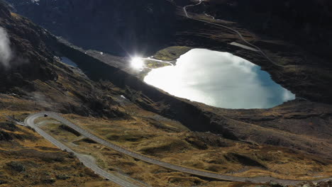 toma aérea cinematográfica del lago steinsee a lo largo del paso susten, suiza, con una llamarada solar