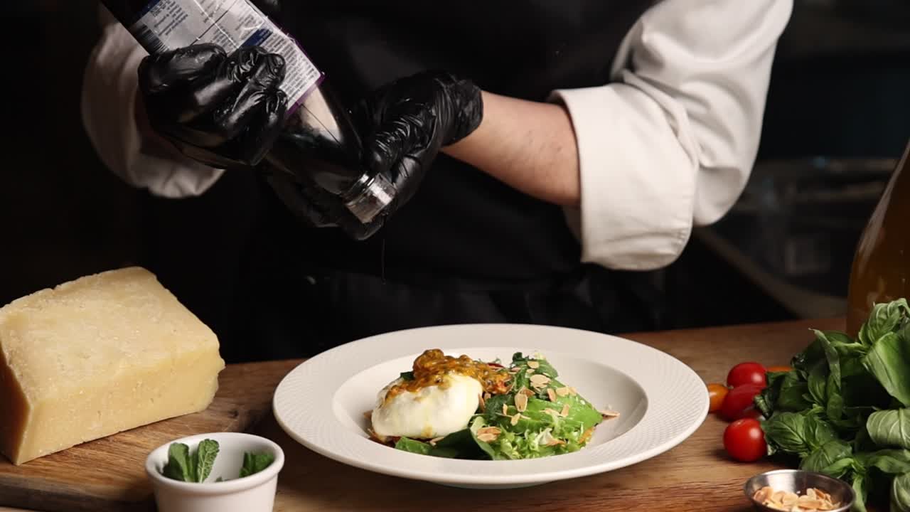 Chef Drizzling Balsamic Glaze on a Fresh Burrata Salad