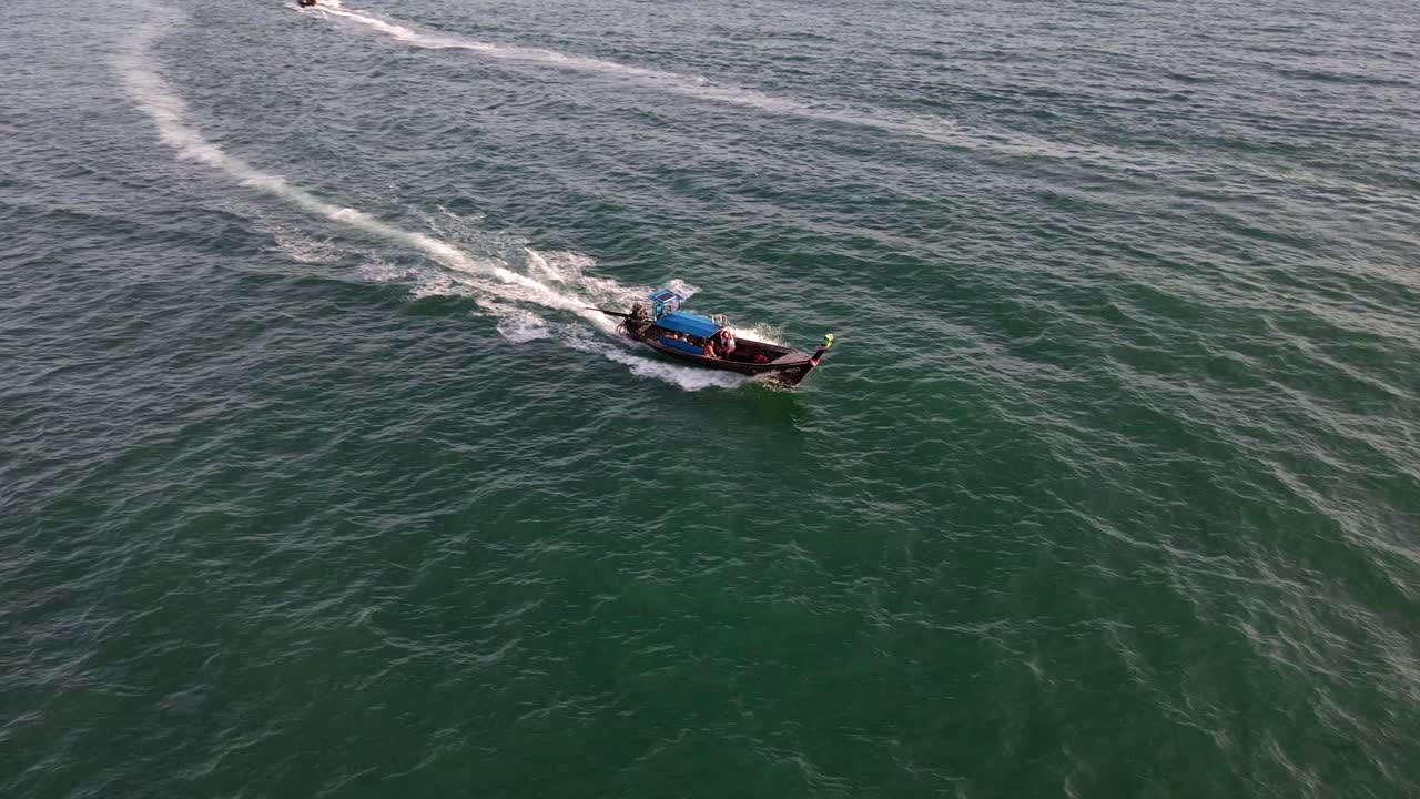 저녁 시간에 태국 끄라비 아오낭 해변을 따라 돌아다니는 긴꼬리 관광선 위를 비행하는 공중 드론