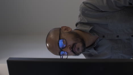 macho adulto de minoría étnica trabajando en un escritorio, visto detrás del monitor