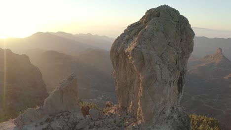 Beautiful-drone-shot-at-golden-hour-with-lens-flare-of-a-mountain-panorama-of-roque-nublo,-gran-canaria