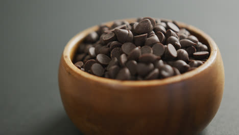 video de primer plano de un cuenco de madera de trozos de chocolate sobre un fondo gris